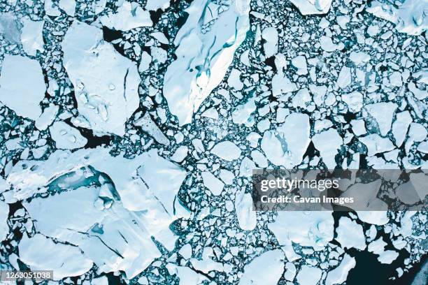 overhead aerial shot of ice floes in beautiful blue color shot in iceland in winter - melting ice stock pictures, royalty-free photos & images