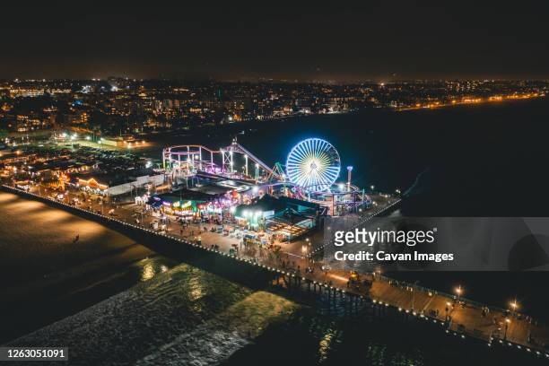 circa november 2019: santa monica pier at night in super colourful lights from aerial drone perspective in los angeles, california - santa monica skyline stock pictures, royalty-free photos & images