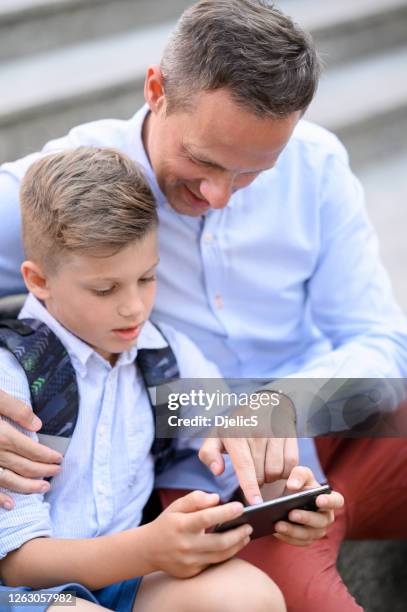 vater und sohn telefonieren gemeinsam. - schulkinder eltern stock-fotos und bilder