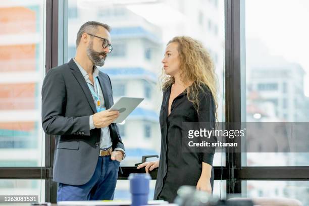 caucasian business man and woman stand and discuss together in the office - coworker conflict stock pictures, royalty-free photos & images