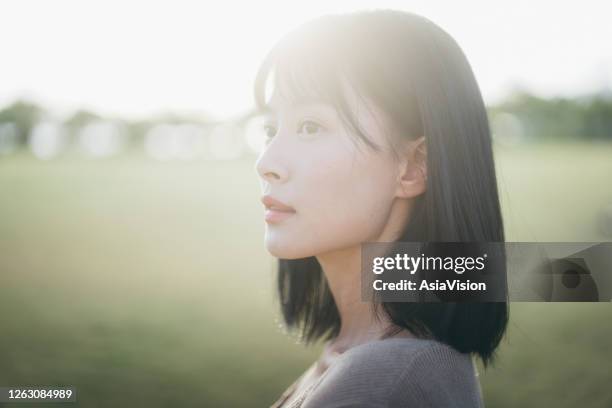 unbekümmerte und heitere junge asiatische frau entspannen im park, genießen das sonnenlicht und die natur - girls sunbathing stock-fotos und bilder