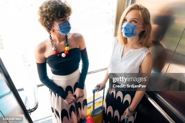 hotel guests riding an elevator with protective face masks - social distancing elevator stock pictures, royalty-free photos & images