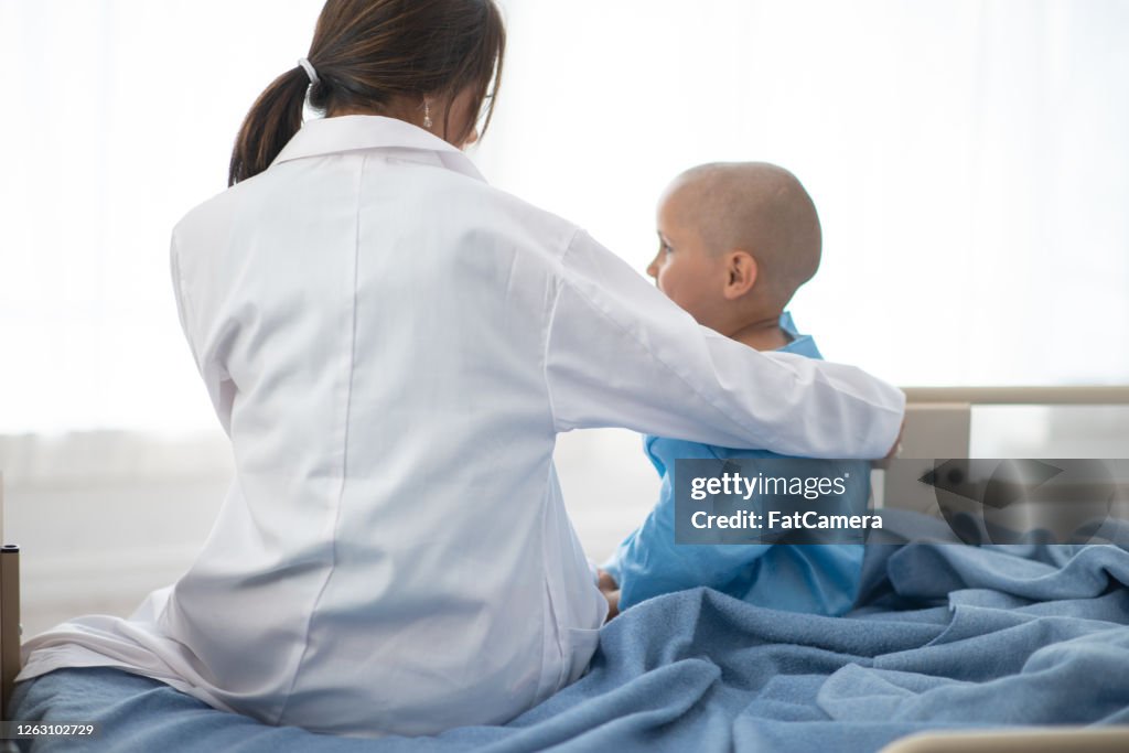 Doctor with arm around young cancer patient