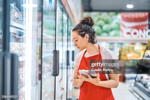 saleswoman in apron working at supermarket - supermarket fridge stock pictures, royalty-free photos & images