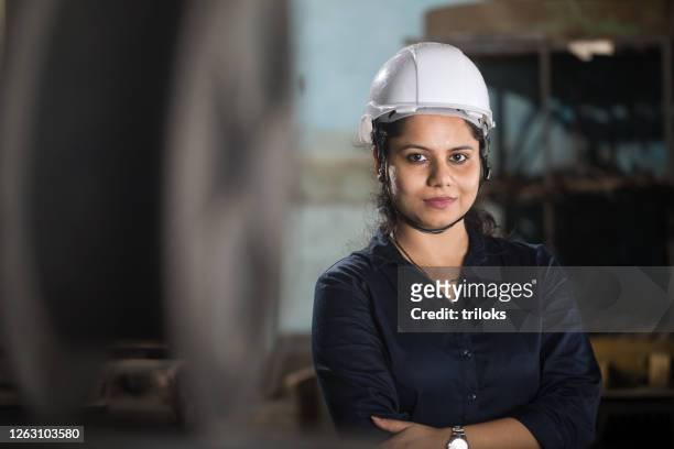 selbstbewusste ingenieurin mit gekreuzten armen in der fabrik - indian engineer stock-fotos und bilder