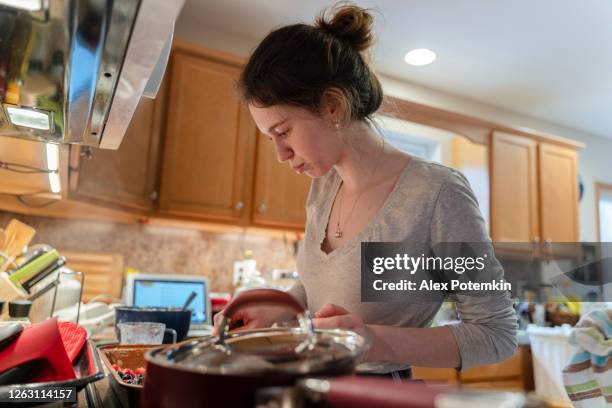 young adult woman spreading filling in a cooking pan. - crowded kitchen stock pictures, royalty-free photos & images