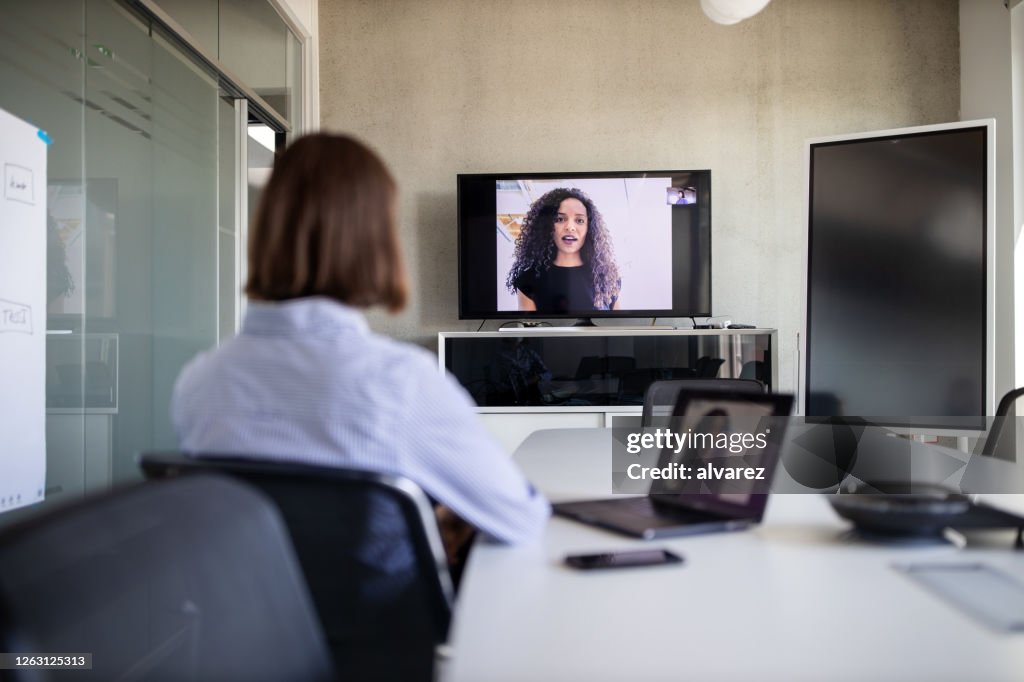 Empresaria planeando con un compañero de trabajo en videollamada