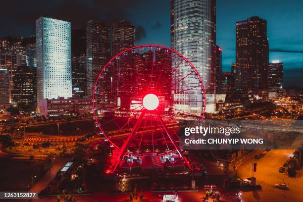 hong kong observation wheel against skyscrapers and modern buildings near central pier. - ferry wheel stock pictures, royalty-free photos & images