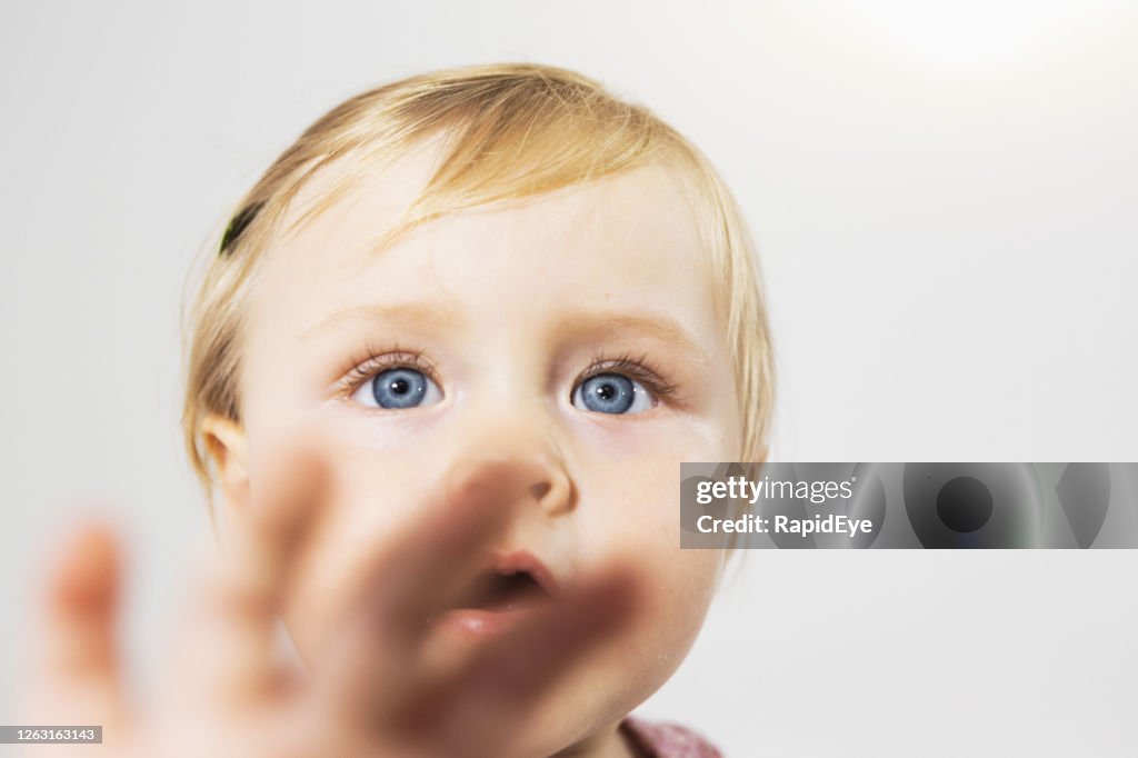 Cute toddler girl child gestures at the camera as if making a Stop sign