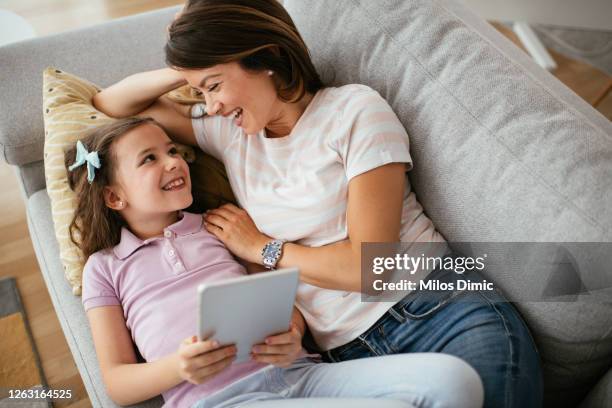 happy mom and little daughter relax using tablet together stock photo - preschool student stock pictures, royalty-free photos & images