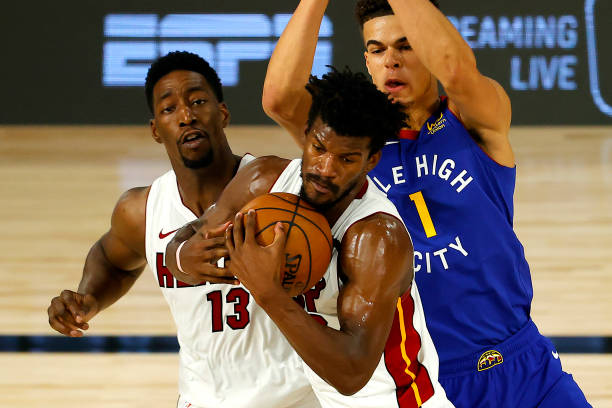 Jimmy Butler of the Miami Heat is fouled by Michael Porter Jr. #1 of the Denver Nuggets as Bam Adebayo of the Miami Heat looks on at HP Field House...