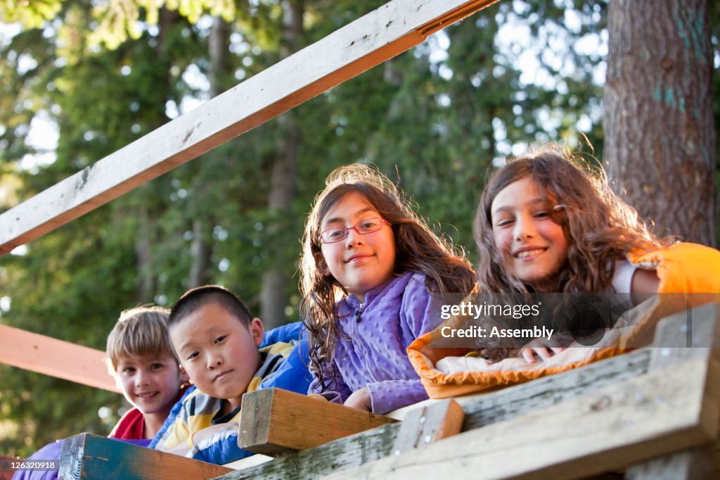 Kids hang out in sleeping bags in a tree house