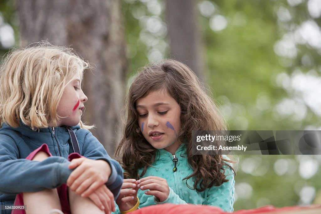 Two girls talk while camping in woods