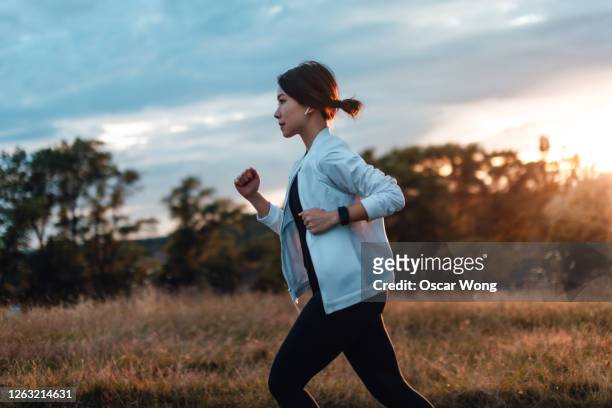 young woman running at the park at sunset - jogging photos et images de collection