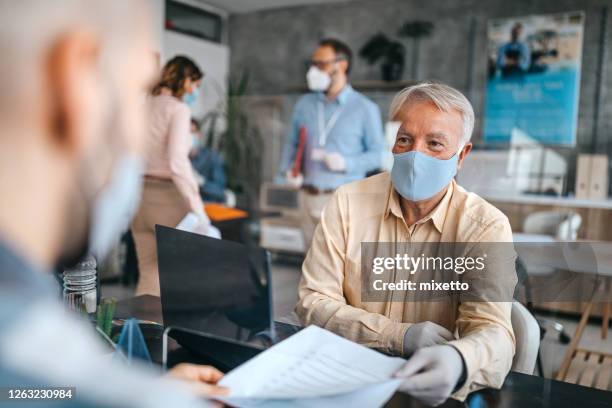 medewerkers die met beschermende gezichtsmaskers bij bank werken - bank counter old stockfoto's en -beelden