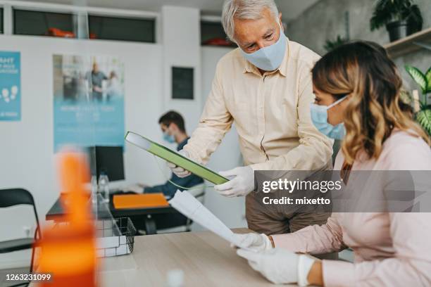 medewerkers die met beschermende gezichtsmaskers bij bank werken - bank counter old stockfoto's en -beelden