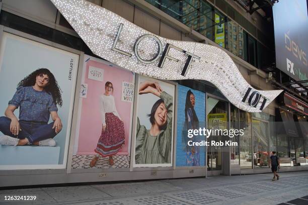 Person wearing a protective face mask walks by a Ann Taylor LOFT retail store in Times Square during Phase 4 of re-opening following restrictions...