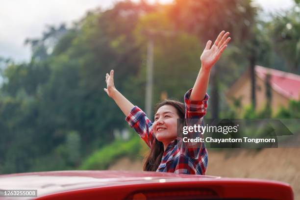 freedom car travel concept. a happy young woman takes the hand out of the window of a car - autostop stock-fotos und bilder