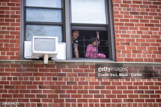 Mother and young child watch the protesters out the window as they pass their neighborhood at the Black Lives Matter protest in Bayside, Queens. This...