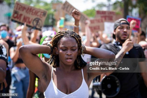 Kiara Williams, an organization leader of Warriors in the Garden in front of protesters with signs and raised fists as they walk through...