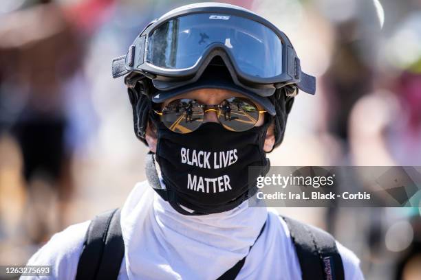 Protester wearing a mask that says, "Black Lives Matter" and ski goggles in case of another round of police conflict and pepper spray as they walk...