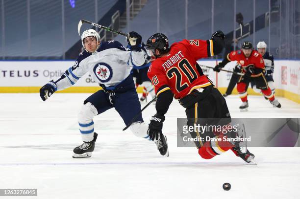 Derek Forbort of the Calgary Flames tries to turn as Jack Roslovic of the Winnipeg Jets skates for the puck in the second period of Game One of the...