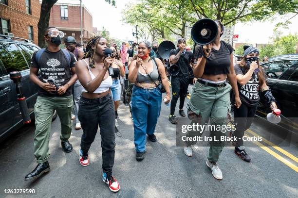 Members of the Warriors in the Garden with megaphones and microphones lead a crowd of protesters leads the crowd as they walk through neighborhoods...