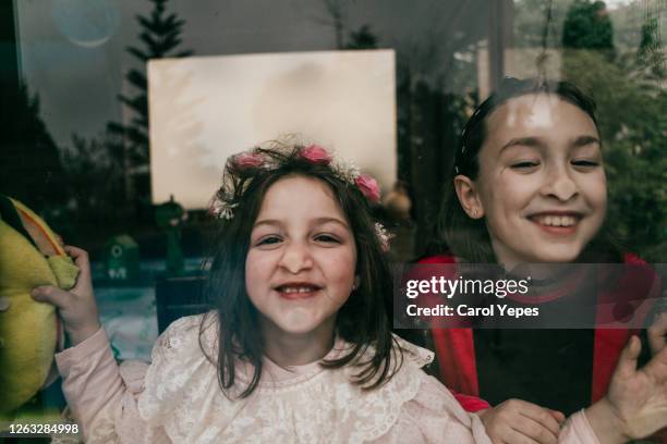 two girls having fun pressing face against window glass and making funny faces - children funny moments stock pictures, royalty-free photos & images