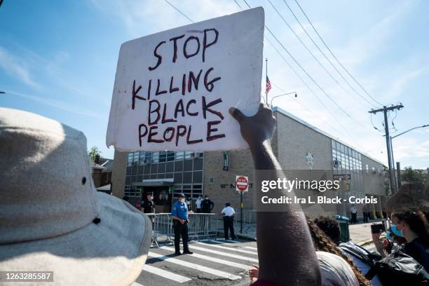 Protester holds a sign that says, "Stop Killing Black People" as the crowd stands in front of then 111 New York Police Department Precinct with...