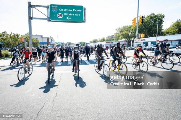 Line of bicycle riders lead the way and help block traffic for the protesters past a highway sign for Clearview Expressway during the Black Lives...