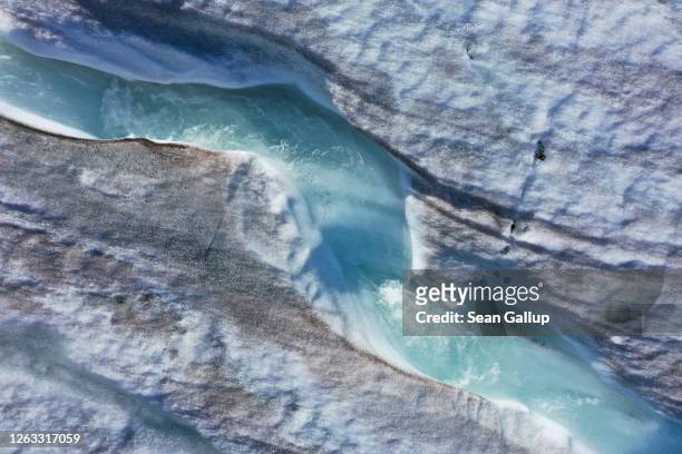 In this aerial view from a drone water carves a winding channel down the surface of the melting Longyearbreen glacier during a summer heat wave on...