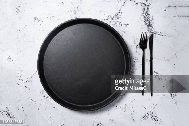 black cast iron plate pan with eating utensil - overhead view photos et images de collection