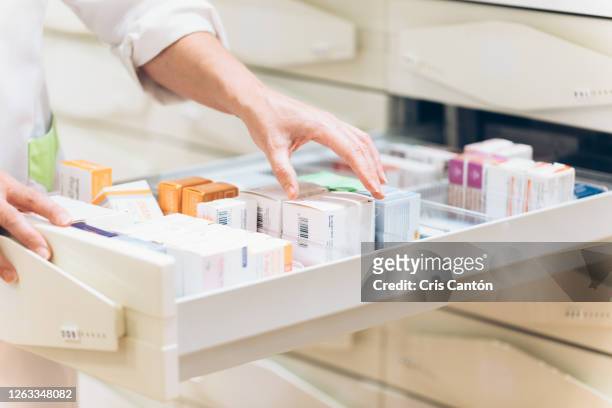 pharmacist hand taking medication from drawer - tratamiento fotografías e imágenes de stock