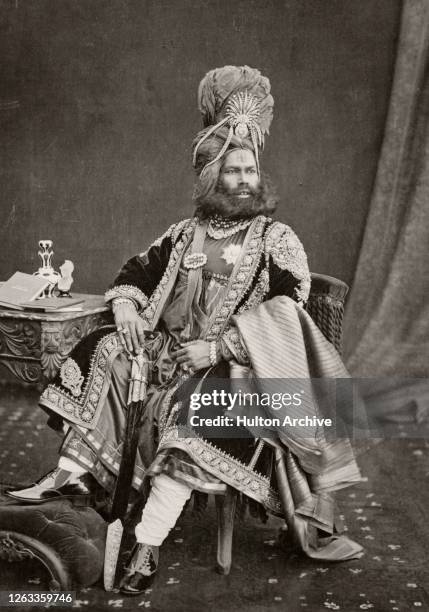 Maharajah of Panna Rudra Pratap Singh wearing a decorated turban with pearls suspended from either side, and a long cloak decorated with brocade, his...