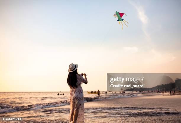 asian adult playing kite on the beach - indonesian kite stock pictures, royalty-free photos & images