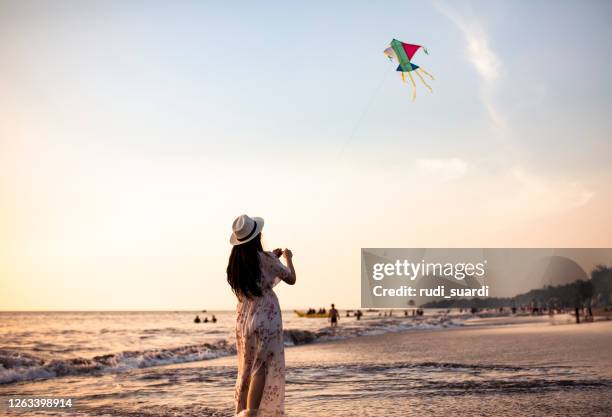 asian adult playing kite on the beach - kite flying stock pictures, royalty-free photos & images