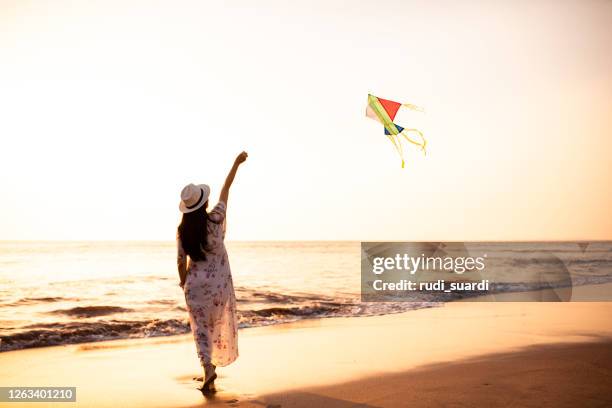 asian adult playing kite on the beach - indonesian kite stock pictures, royalty-free photos & images