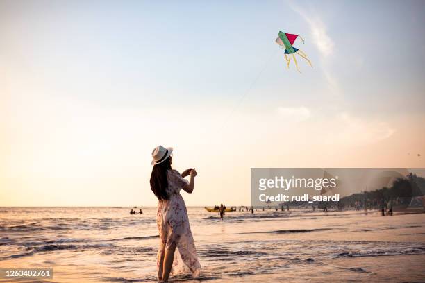 asian adult playing kite on the beach - indonesian kite stock pictures, royalty-free photos & images