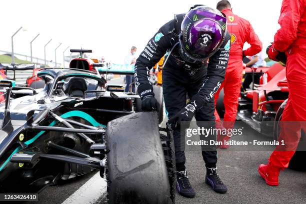 Lewis Hamilton of Great Britain and Mercedes GP inspects his punctured tyre in parc ferme after the Formula One British Grand Prix at Silverstone on...