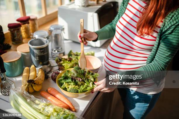 mujer embarazada sana preapring una ensalada orgánica fresca para su desayuno - ensalada verde fotografías e imágenes de stock