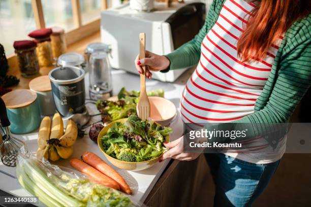 healthy pregnant woman preapring a fresh organic salad for her breakfast - food and drink stock pictures, royalty-free photos & images