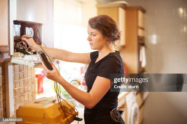 female heating engineer servicing a boiler - kitchen boiler stock pictures, royalty-free photos & images