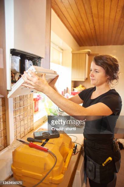 vrouwelijke loodgieter die een boiler herstelt - kitchen straighten stockfoto's en -beelden