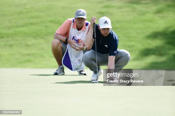 Daniel Berger of the United States looks over a putt with his caddie on the 17th green during the final round of the World Golf Championship-FedEx St...