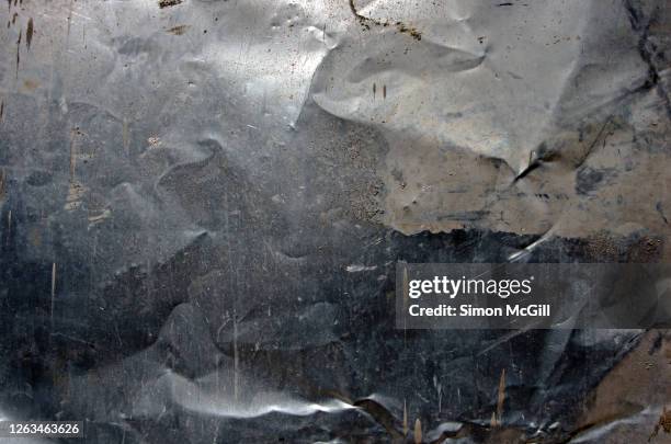 crumpled, dented, scratched and mud splattered stainless steel metal sheet - metal texture stockfoto's en -beelden