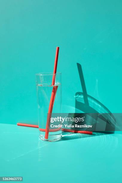 red drinking straws in a glass on  turquoise background - glas wasser stock-fotos und bilder