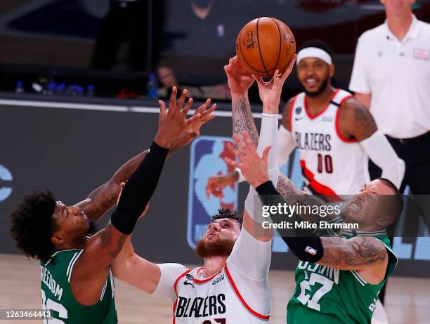 Jusuf Nurkic of the Portland Trail Blazers goes up for a loose ball against Daniel Theis and Marcus Smart of the Boston Celtics at The Arena at ESPN...