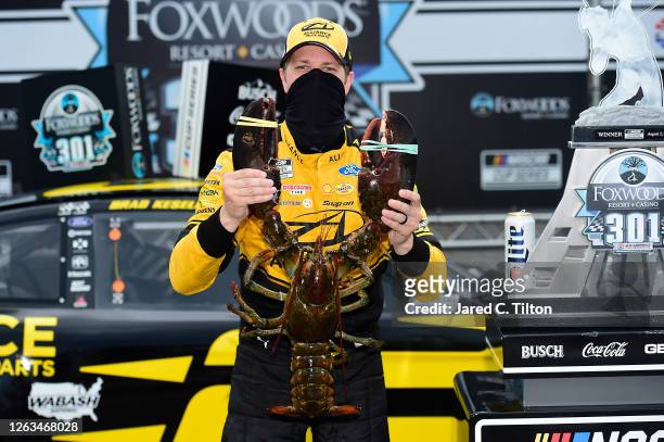 Brad Keselowski, driver of the Western Star/Alliance Parts Ford, poses for a photo with Loudon the Lobster in Victory Lane after winning the NASCAR...