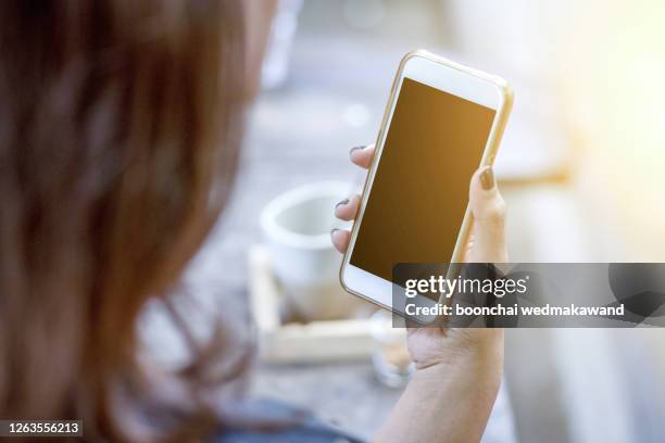 girl using and showing a blank phone screen lying on a couch at home - rug handen zij stockfoto's en -beelden