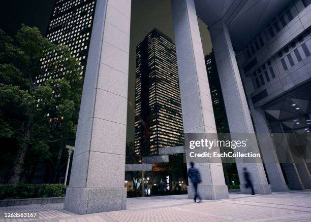 businessmen going home late at shinjuku business district, tokyo, japan - kolonnade stock-fotos und bilder